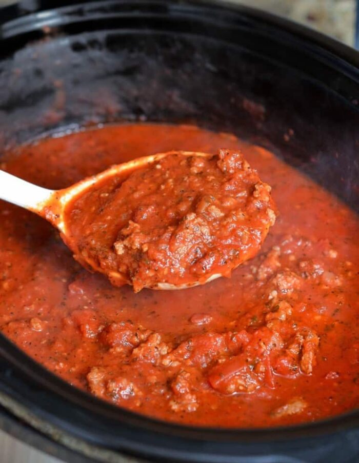 spaghetti sauce in the slow cooker with a laddle
