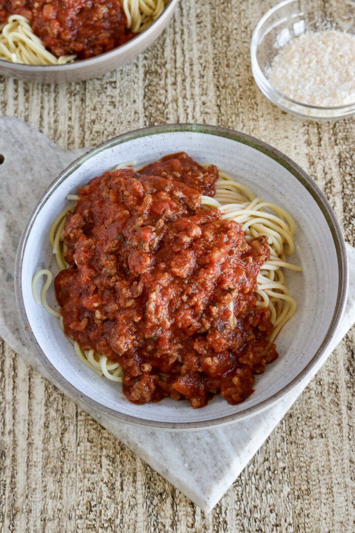 Spaghetti sauce in the slow cooker served over butter spaghetti noodles in a bowl