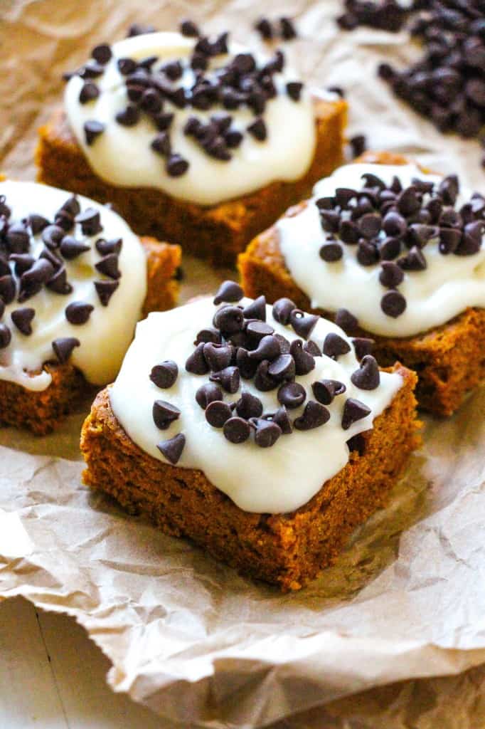 Side angle shot of pumpkin bars with cream cheese frosting and chocolate chips