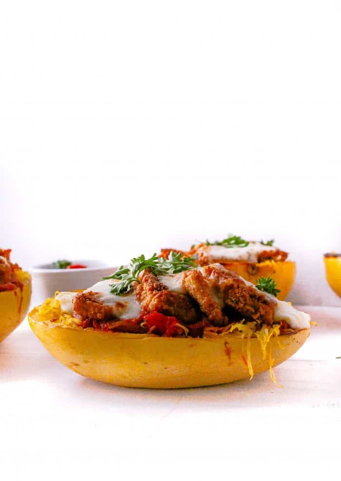 Spaghetti squash boats with crispy chicken, marinara, and topped with fresh herbs