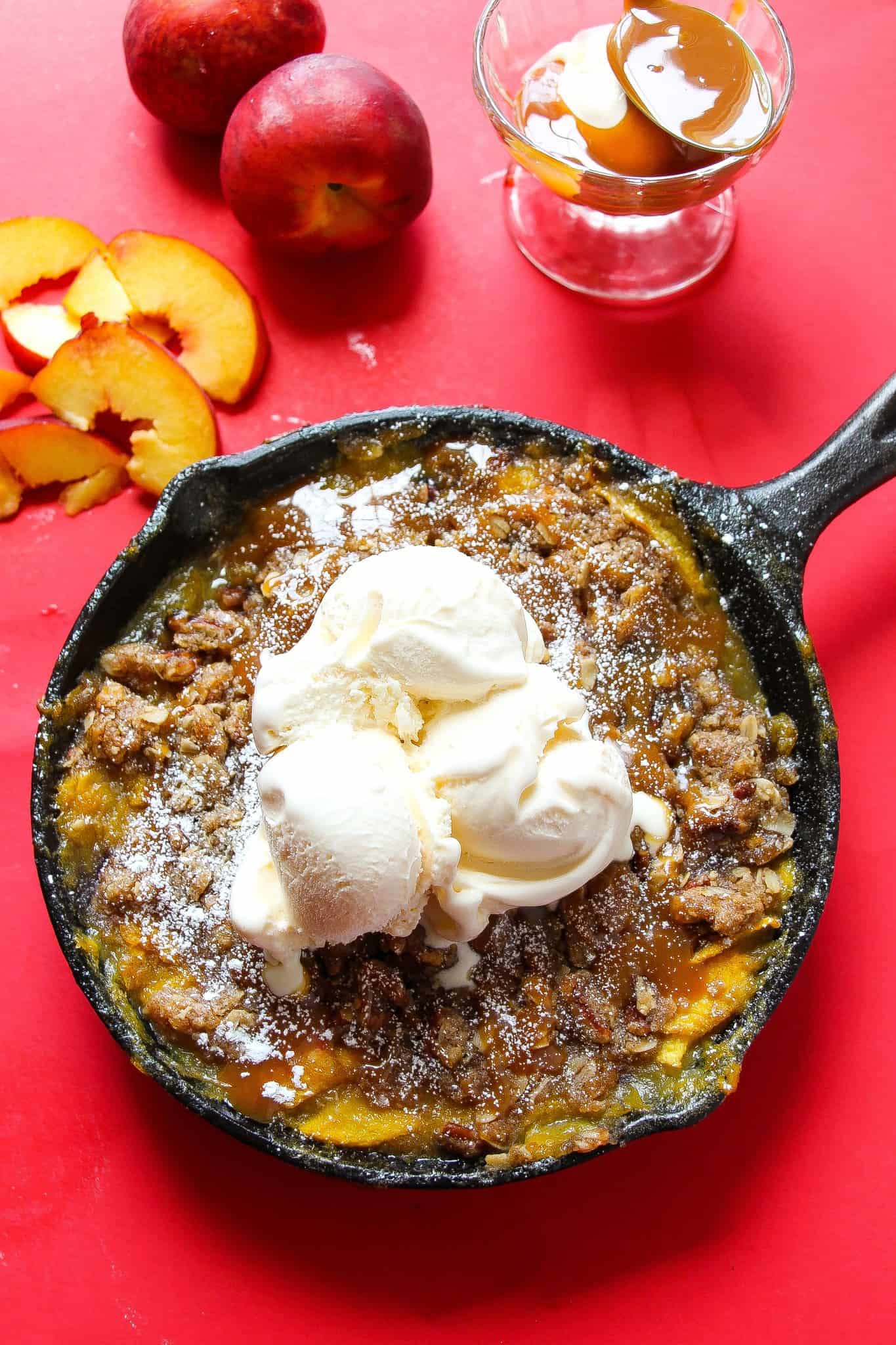 Peach crisp topped with ice cream and served warm
