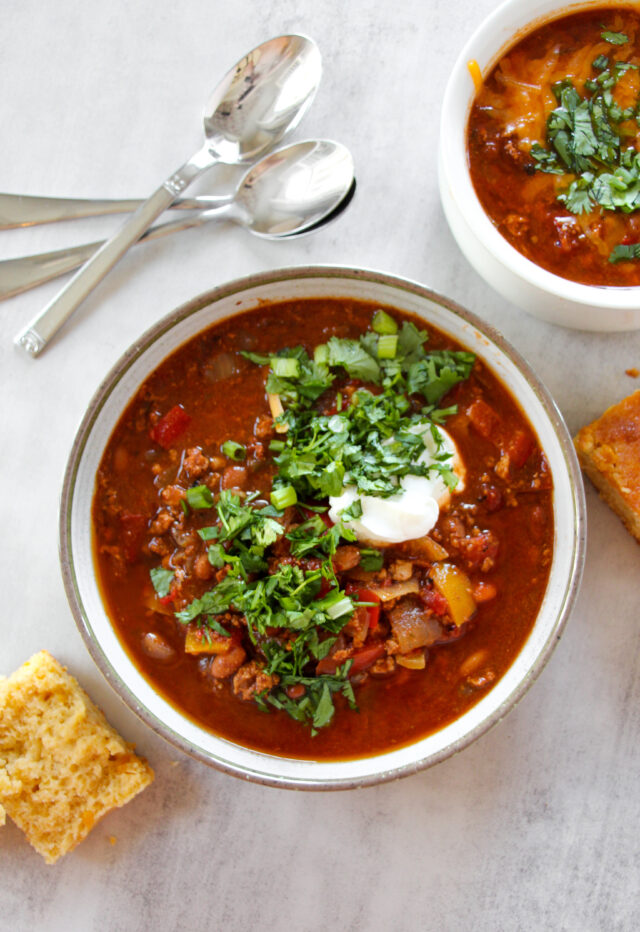Mild chili recipe served in a bowl with sour cream on top and cornbread