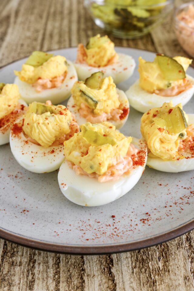 Deviled eggs with pimento cheese on the bottom and a pickle on top
