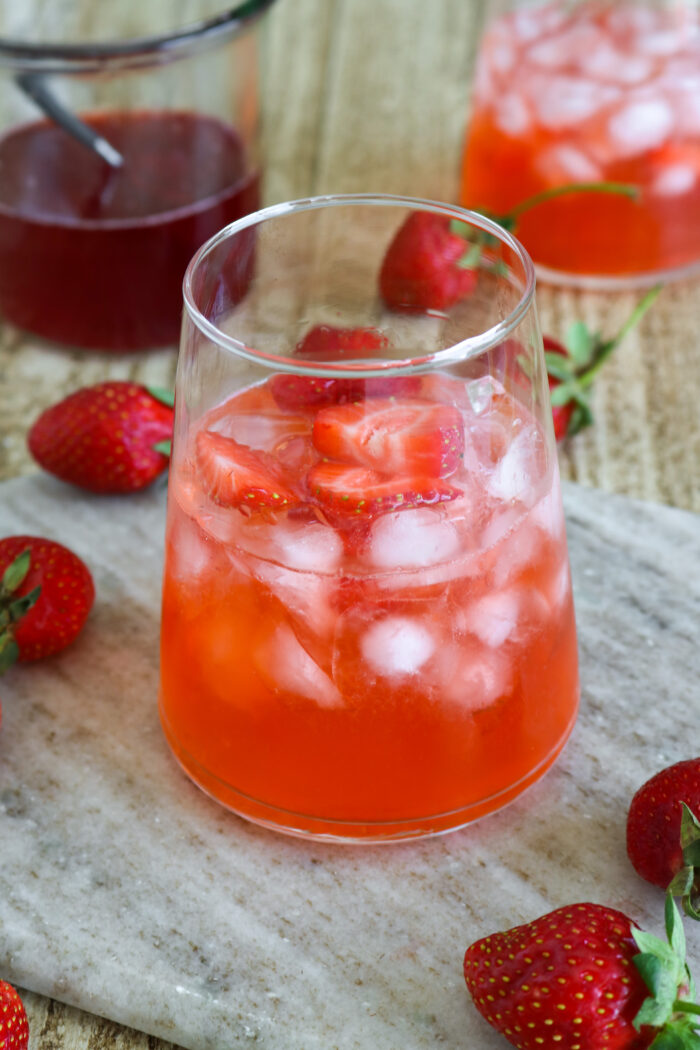 Side photo of a strawberry syrup cocktail topped with fresh strawberries