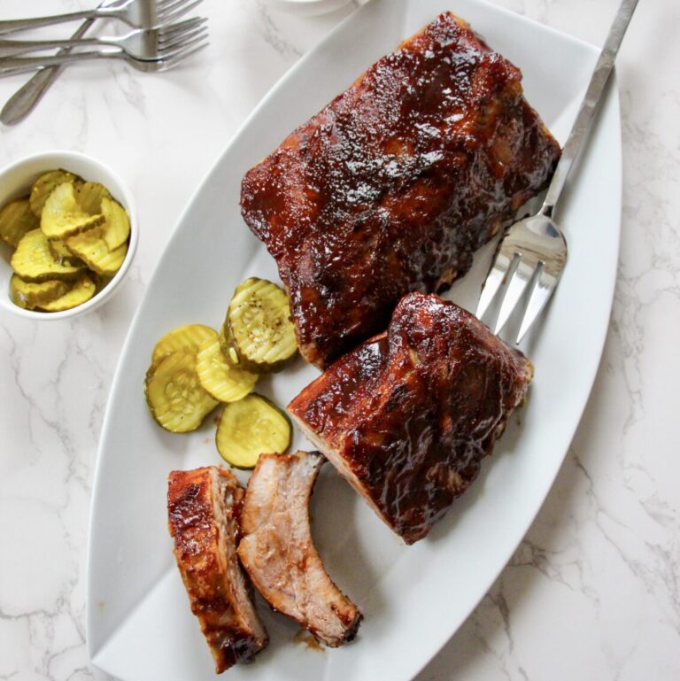 The finished ribs on a plate with pickles on the side