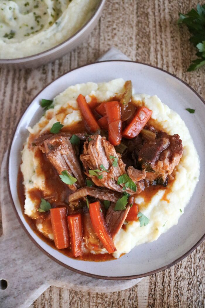 Dutch Oven Pork Roast served over mashed cauliflower with parsley on top