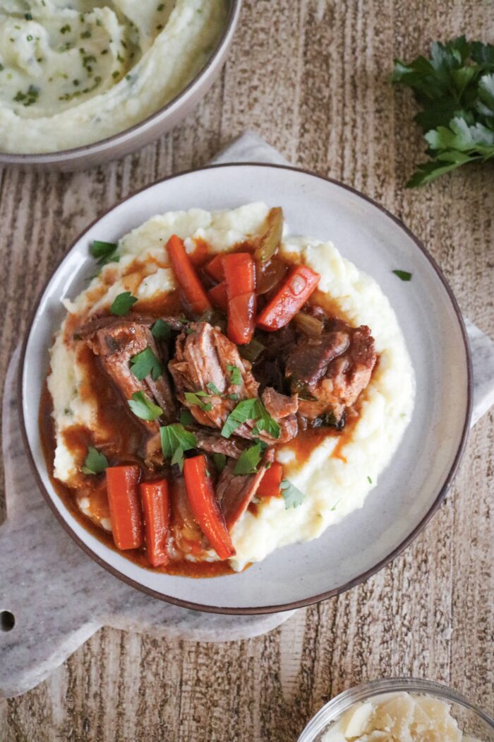 Dutch Oven Pork Roast served over mashed cauliflower with parsley on top