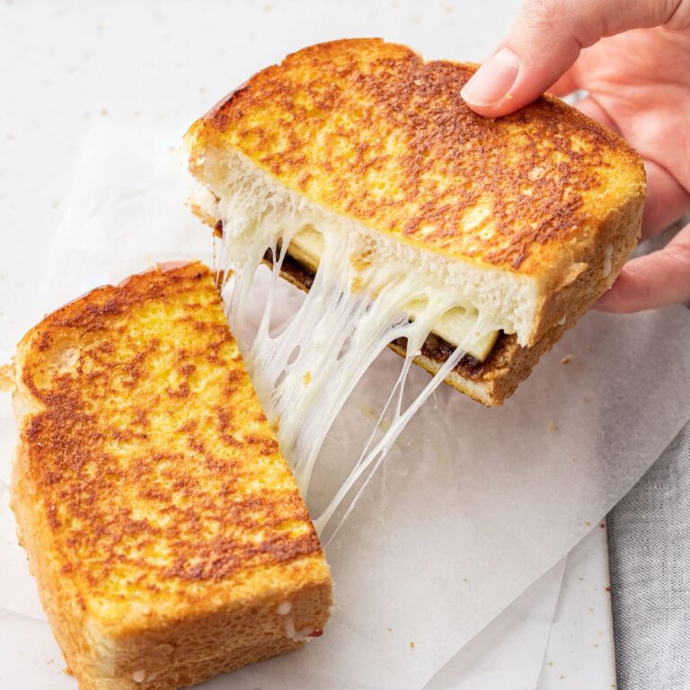 A finished apple butter grilled cheese being pulled apart with a cheese pull in the middle