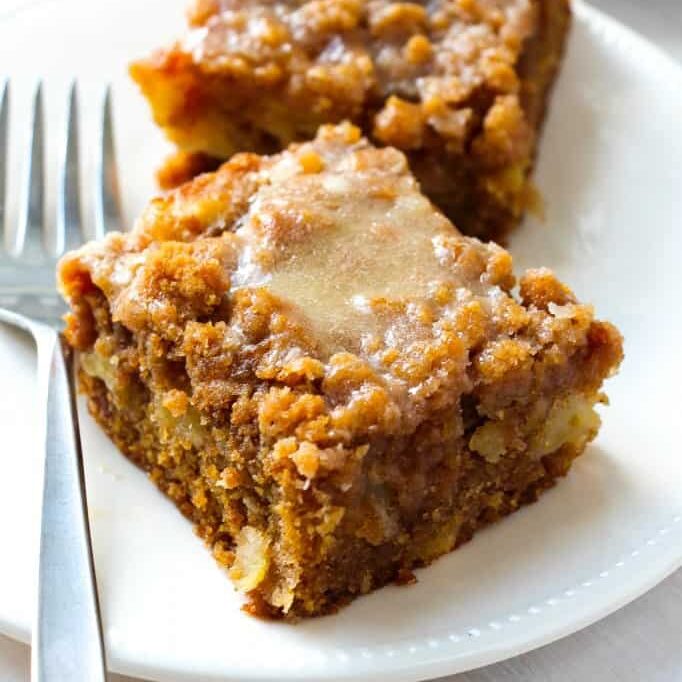 Apple crumb cake with a glaze on top on a plate with a fork