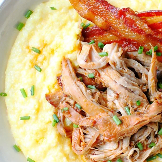 The finished shredded pork tenderloin served over cheesy grits with bacon on the side