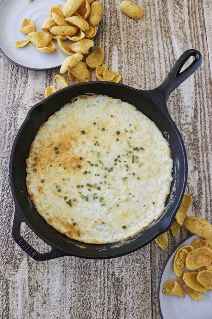 Baked hot onion dip in a cast iron with fritos on the side