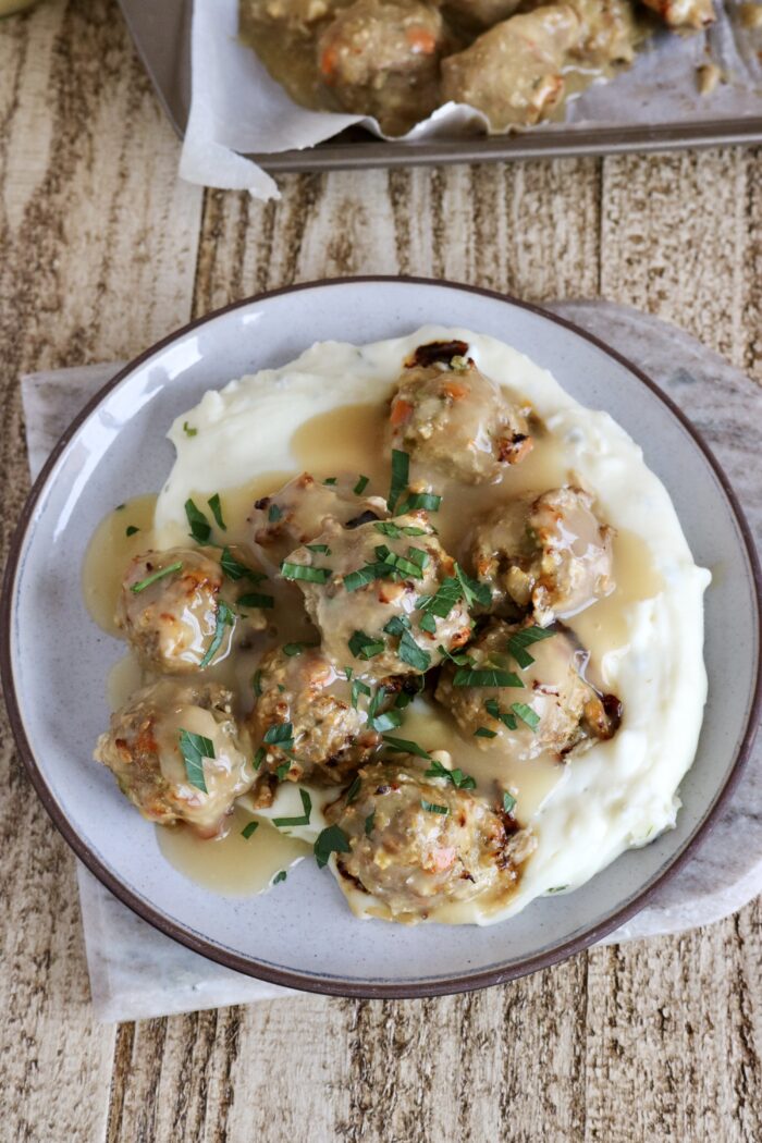 Thanksgiving turkey meatballs on a plate served over mashed potatoes with gravy on top