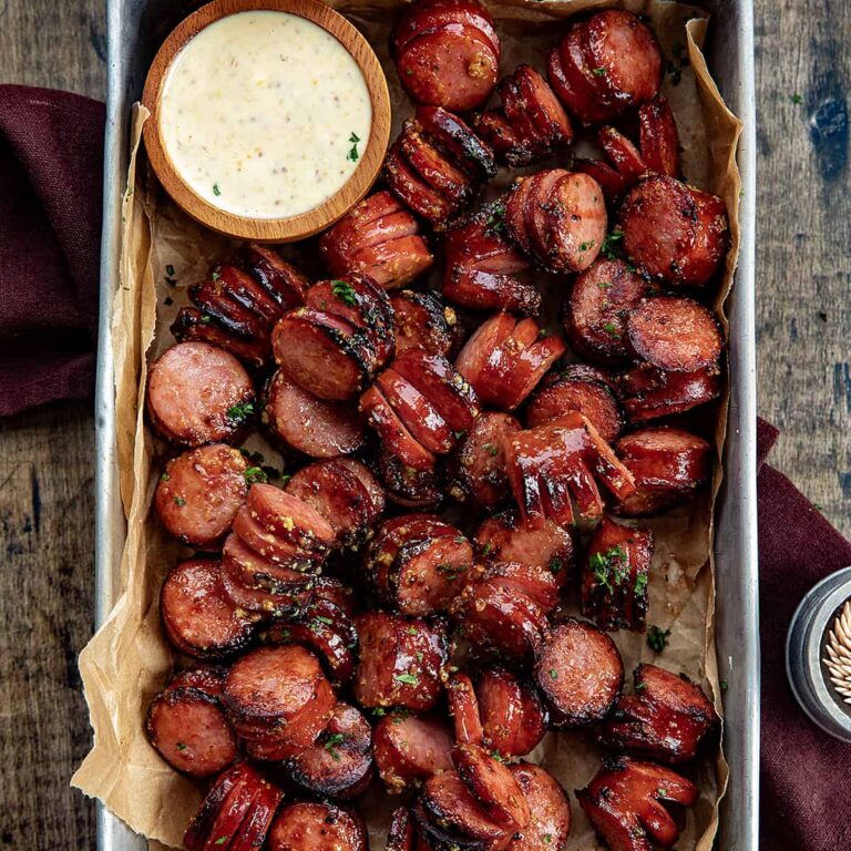 Kielbasa bites in a serving tray with dipping sauce on the side