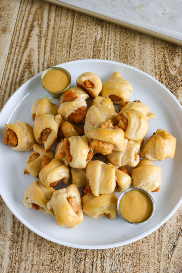 Chicken nuggets in a blanket on a plate with chick fil a sauce