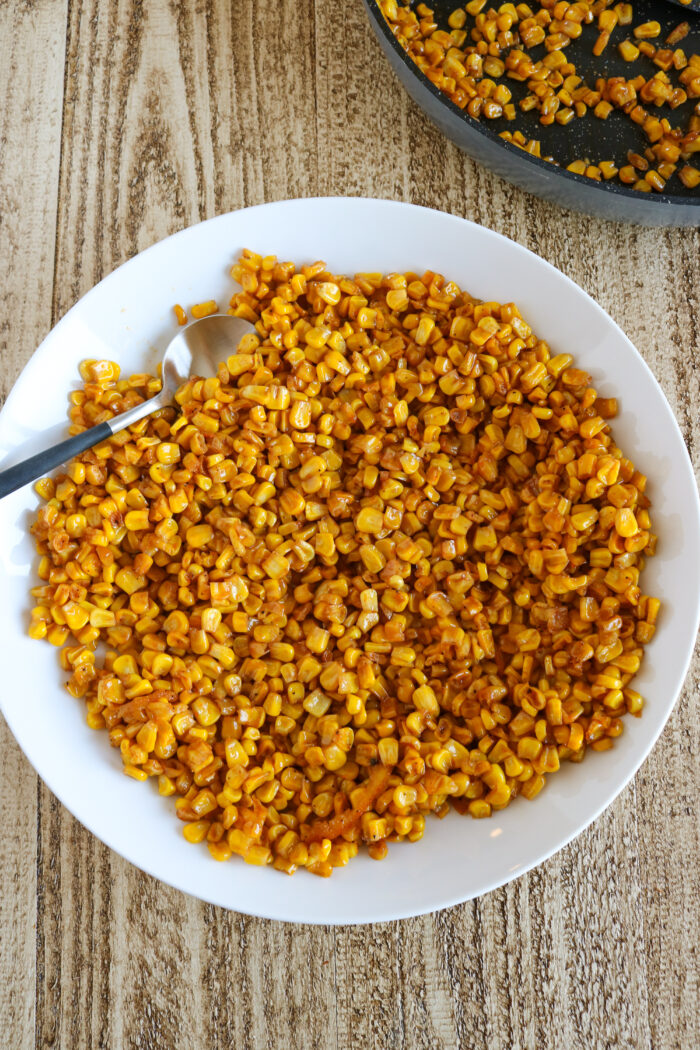 Blackened corn on a plate with a serving spoon in it